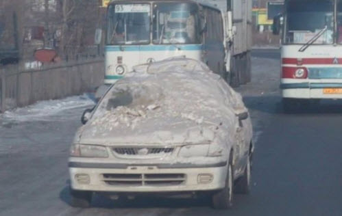 машина под снегом едет по дороге